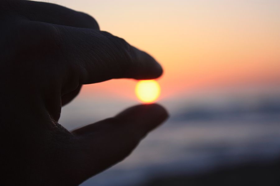 Fotografía de una mano que parece atrapara al sol